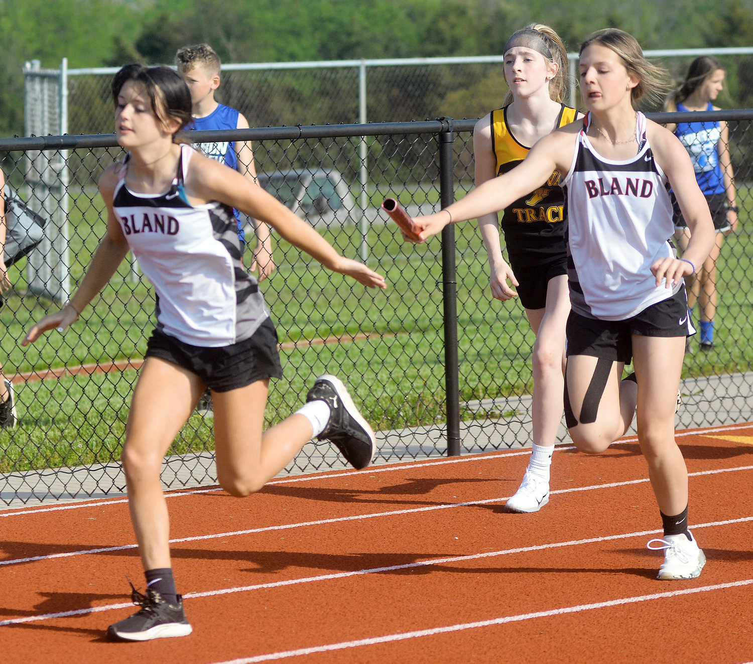 Nolie Finnegan (far left) reaches back for the baton from Anastyn Lansford for Bland’s Lady Bears during the girls 4x200-meter relay.
